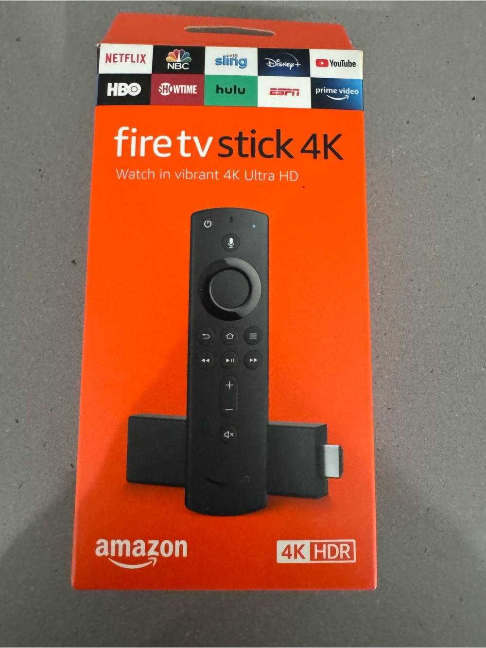 Amazon Fire TV Stick 4K in bright orange retail box with black remote